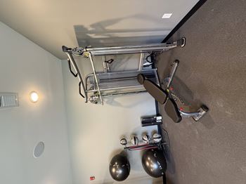 A metal structure is mounted on a wall with two black spheres hanging from it.